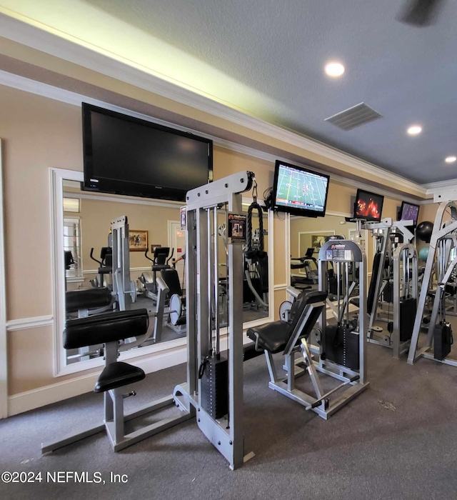 exercise room with a textured ceiling, visible vents, crown molding, and recessed lighting