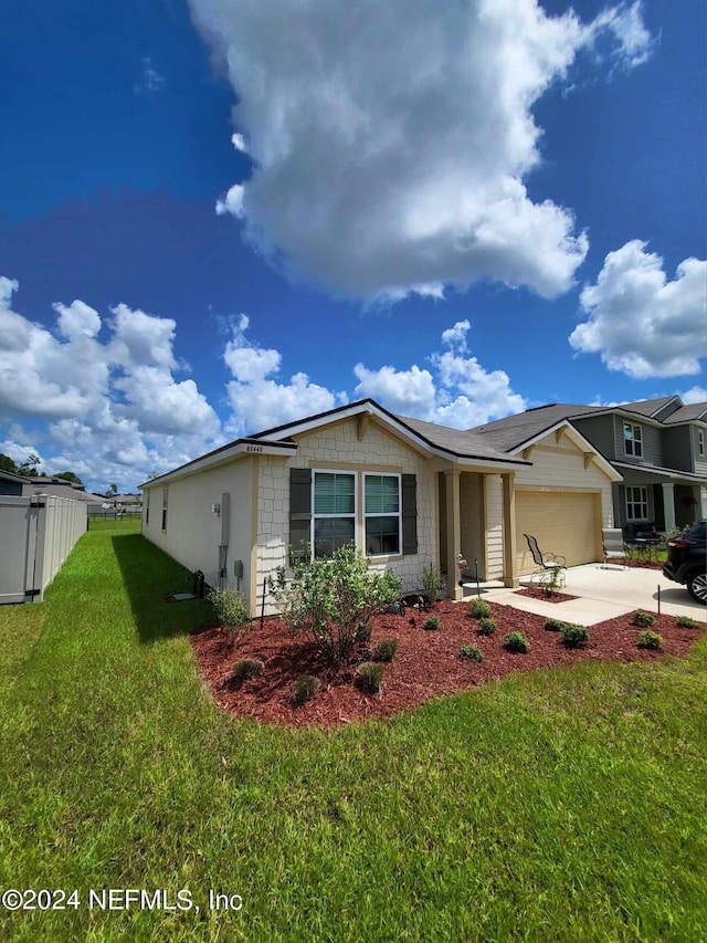 ranch-style house with driveway, a garage, fence, and a front yard