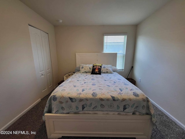 bedroom with a closet, dark carpet, and baseboards