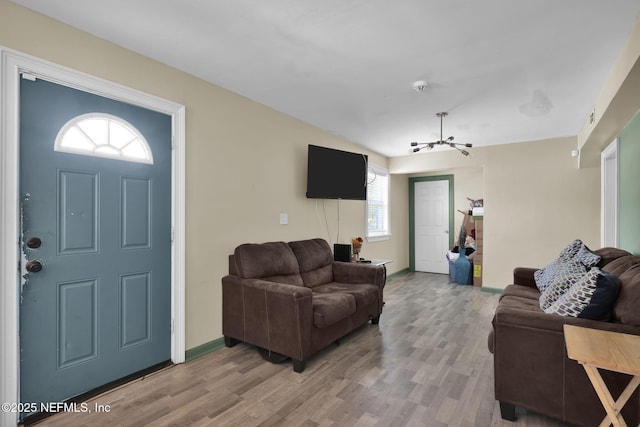 living room featuring an inviting chandelier, baseboards, and light wood-type flooring