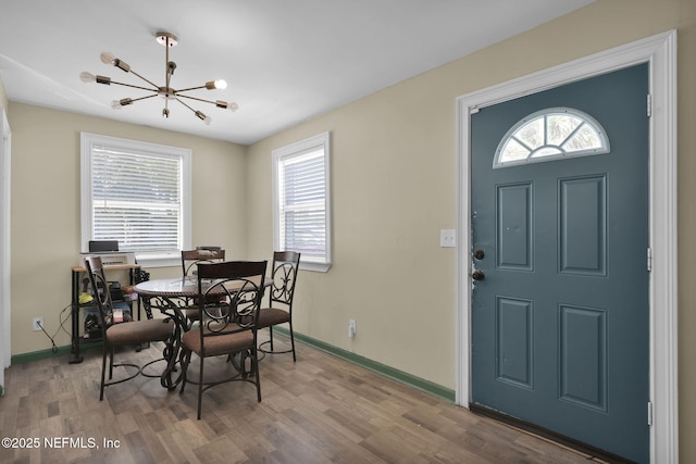 dining room featuring a chandelier, baseboards, and wood finished floors