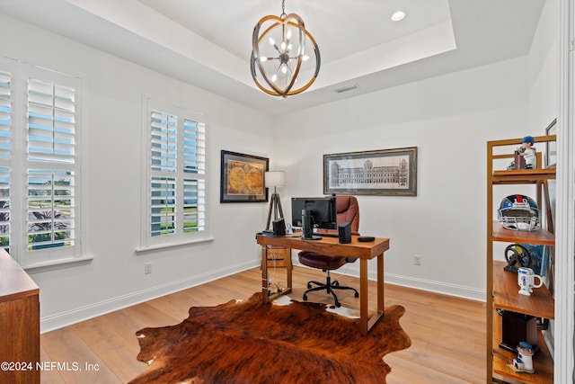 home office featuring a notable chandelier, a raised ceiling, and light hardwood / wood-style floors