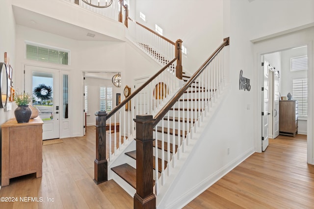 stairway with a towering ceiling, hardwood / wood-style floors, and a chandelier