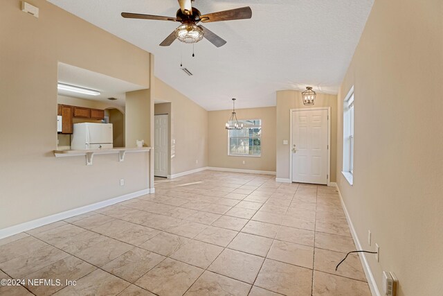 unfurnished living room featuring light tile patterned floors, a textured ceiling, ceiling fan with notable chandelier, and vaulted ceiling