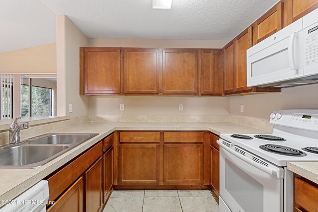 kitchen with white appliances, sink, light tile patterned floors, and a textured ceiling