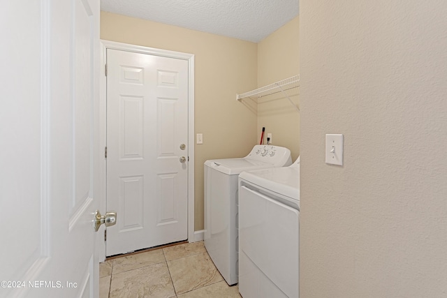 laundry room with a textured ceiling, laundry area, light tile patterned floors, and washing machine and clothes dryer