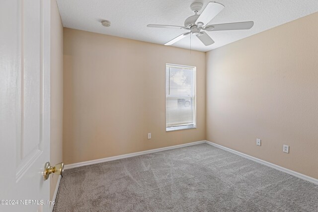 unfurnished room featuring ceiling fan, light colored carpet, and a textured ceiling