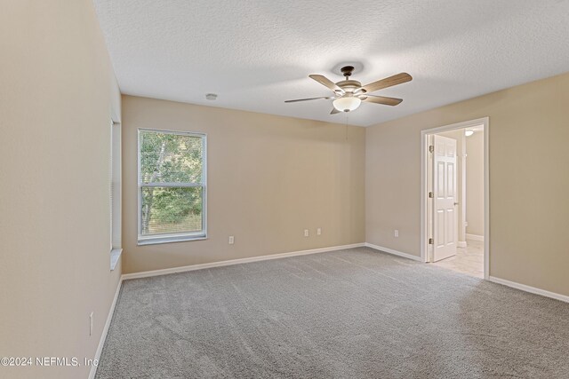 empty room featuring light carpet, ceiling fan, and a textured ceiling