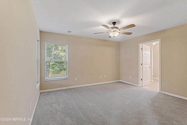 spare room featuring a ceiling fan, baseboards, a textured ceiling, and light colored carpet