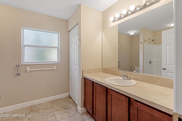 bathroom with walk in shower, vanity, and a textured ceiling