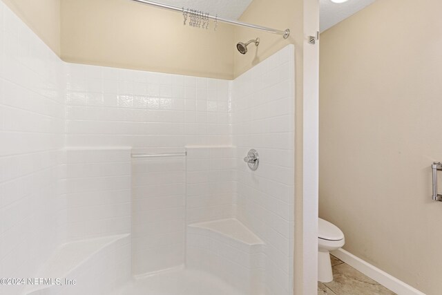 bathroom featuring a shower, a textured ceiling, and toilet