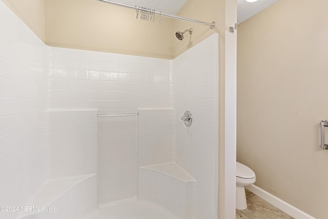 bathroom with toilet, baseboards, walk in shower, and tile patterned floors