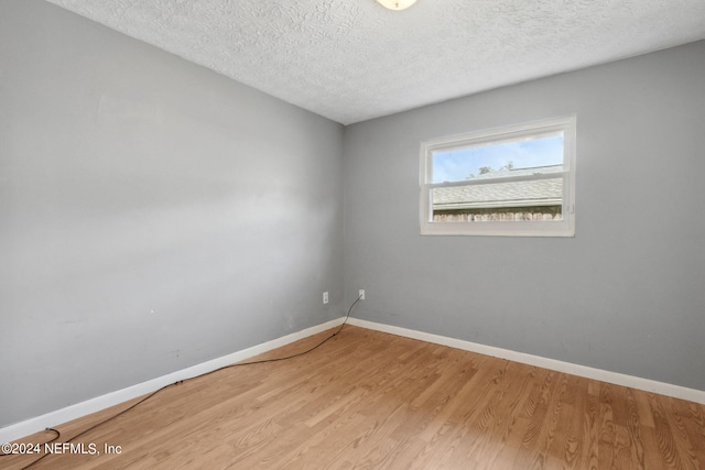 spare room featuring a textured ceiling and light hardwood / wood-style flooring