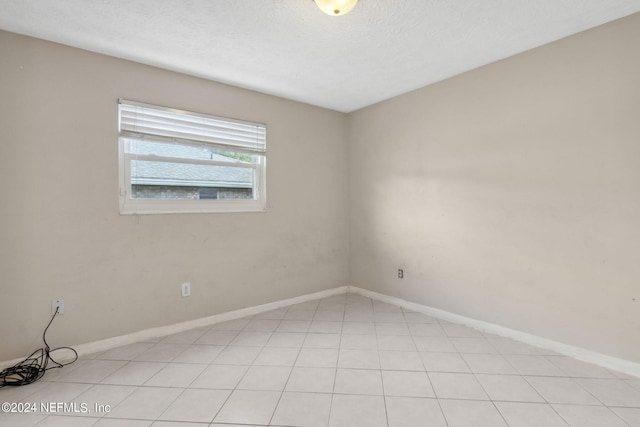 spare room with a textured ceiling and light tile patterned flooring