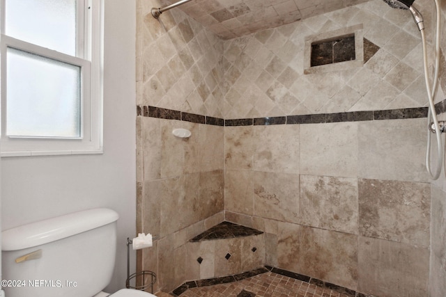 bathroom featuring tiled shower and toilet