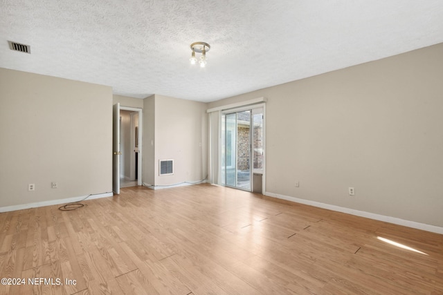 spare room with light wood-type flooring and a textured ceiling