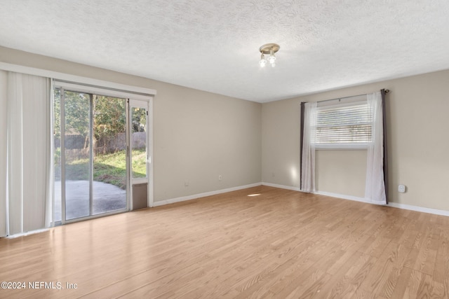 unfurnished room with a textured ceiling, light hardwood / wood-style flooring, and a wealth of natural light