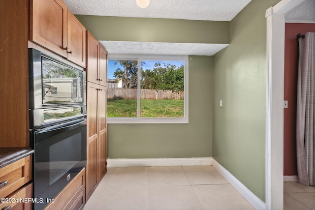 kitchen with black microwave, a wealth of natural light, a textured ceiling, and light tile patterned floors