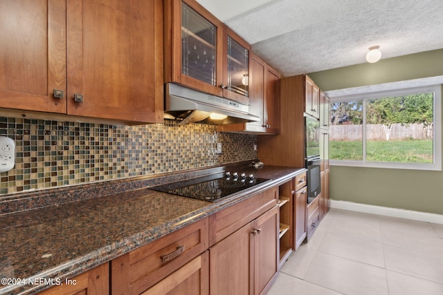 kitchen featuring black electric cooktop, decorative backsplash, dark stone countertops, light tile patterned flooring, and a textured ceiling