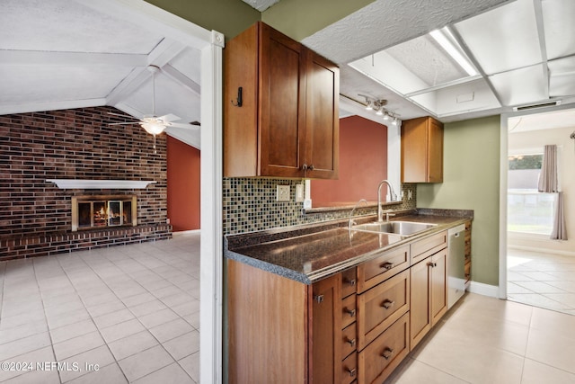 kitchen with light tile patterned flooring, brick wall, lofted ceiling, stainless steel dishwasher, and sink