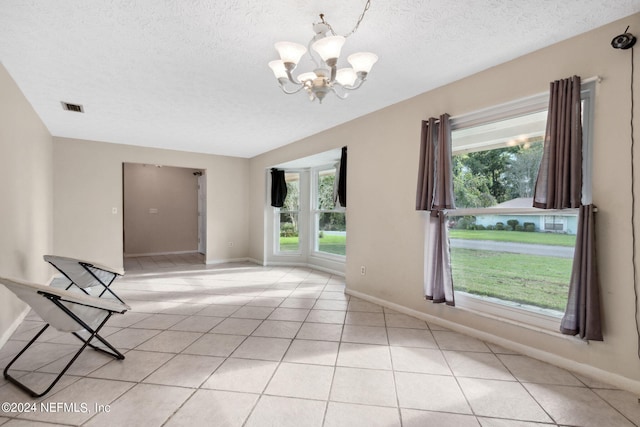 tiled empty room with a textured ceiling and a chandelier