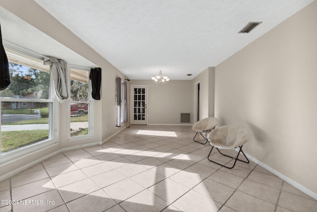 unfurnished room with a wealth of natural light, a chandelier, and light tile patterned floors