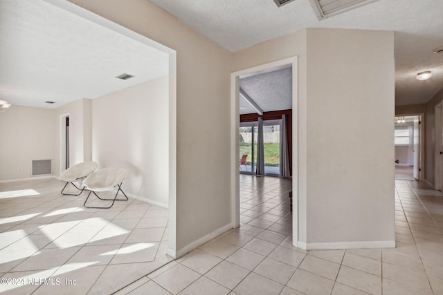 corridor with a textured ceiling and light tile patterned floors