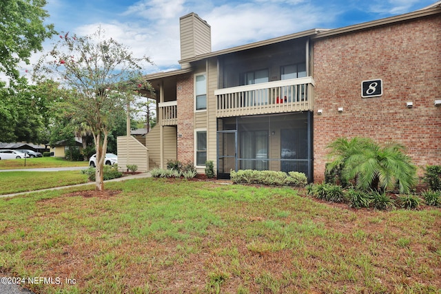 rear view of property featuring a balcony and a lawn