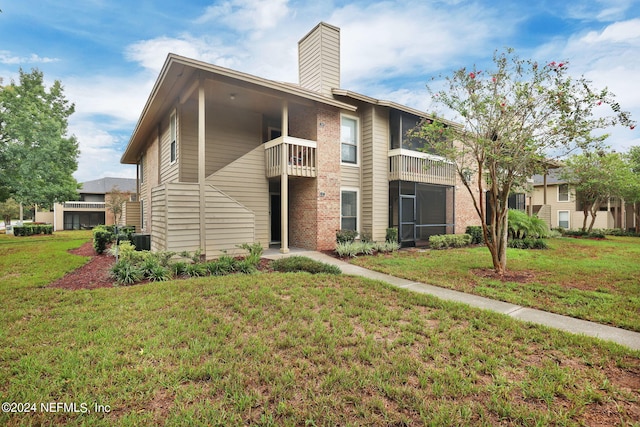 view of front of house featuring a balcony, a front yard, and central AC