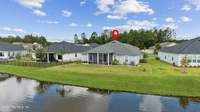 back of house with a water view, a lawn, and a sunroom