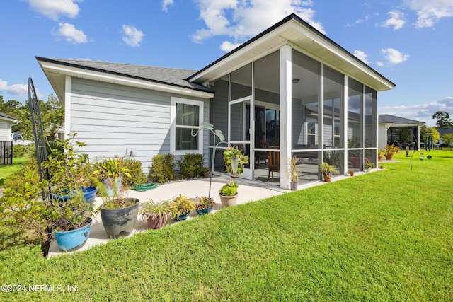 rear view of property with a lawn, a patio, and a sunroom