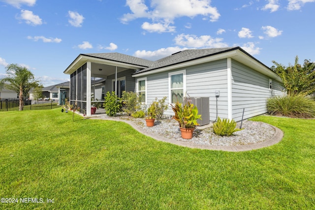 rear view of house featuring a sunroom, a yard, and central air condition unit