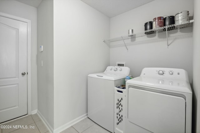 laundry room featuring washing machine and dryer and light tile patterned flooring