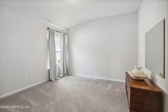 carpeted empty room with lofted ceiling