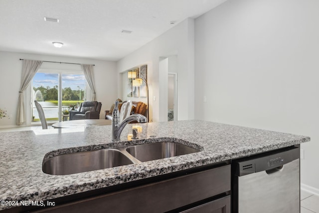 kitchen featuring dishwasher, light stone counters, sink, and light tile patterned flooring