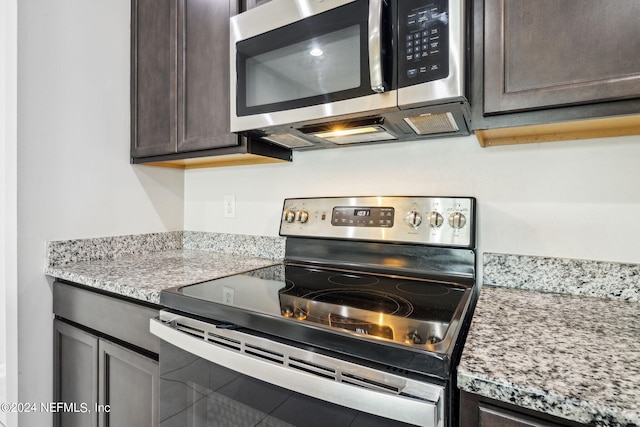 kitchen featuring appliances with stainless steel finishes, light stone countertops, and dark brown cabinetry