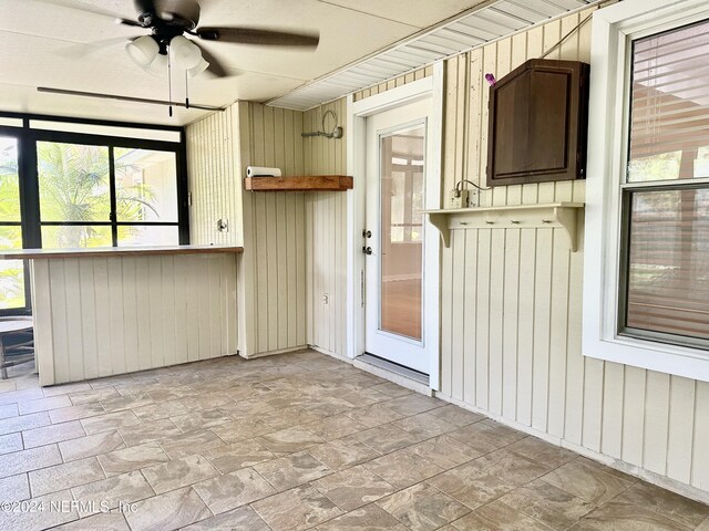 unfurnished sunroom featuring ceiling fan