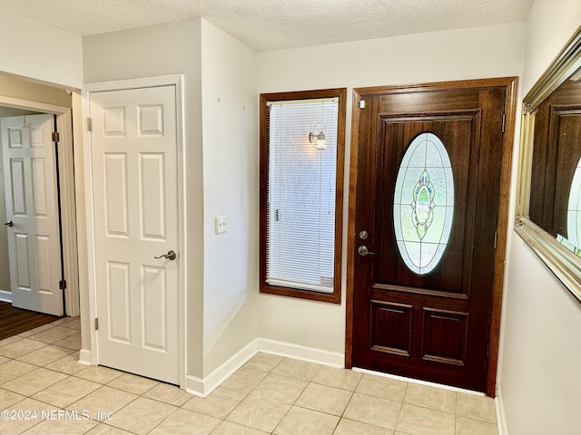 foyer featuring light tile patterned floors, baseboards, and a textured ceiling