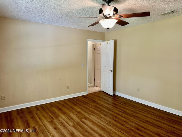 spare room featuring a textured ceiling, ceiling fan, wood finished floors, visible vents, and baseboards