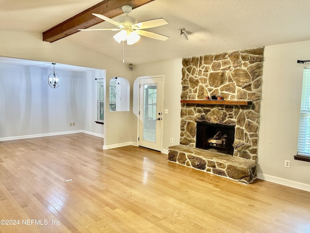 unfurnished living room with a fireplace, lofted ceiling with beams, hardwood / wood-style floors, and a textured ceiling