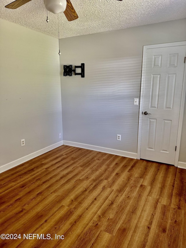 unfurnished room with a ceiling fan, a textured ceiling, baseboards, and wood finished floors