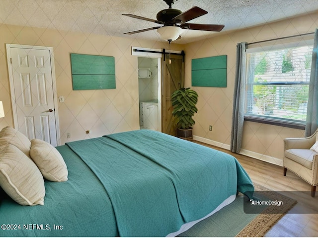 bedroom with ceiling fan, a barn door, and baseboards