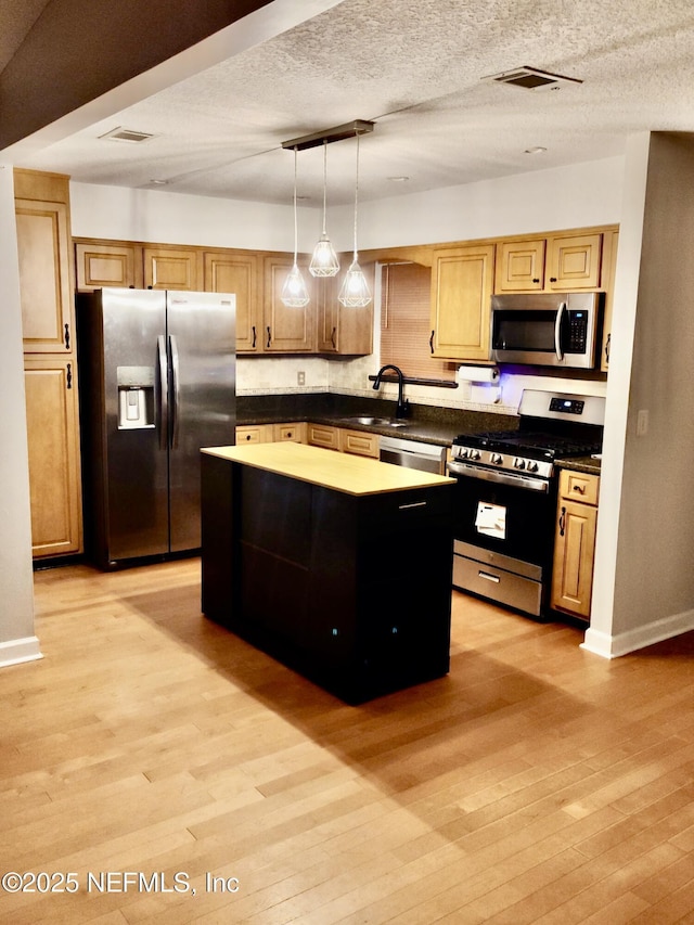 kitchen featuring a kitchen island, pendant lighting, sink, light hardwood / wood-style floors, and stainless steel appliances