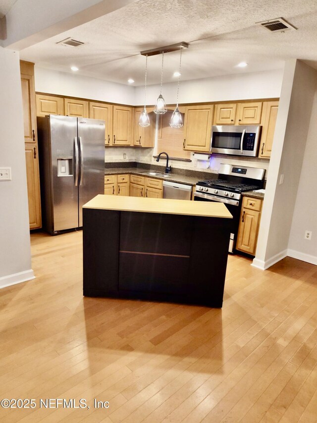 kitchen featuring appliances with stainless steel finishes, light wood-type flooring, a sink, and visible vents