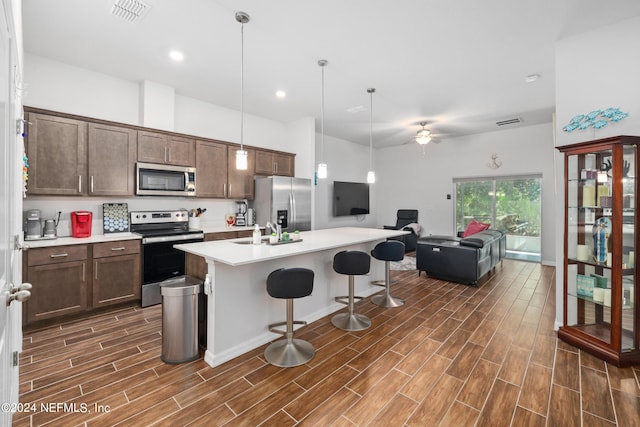 kitchen featuring stainless steel appliances, wood finish floors, visible vents, a kitchen breakfast bar, and light countertops