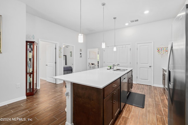 kitchen with appliances with stainless steel finishes, wood tiled floor, light countertops, and visible vents