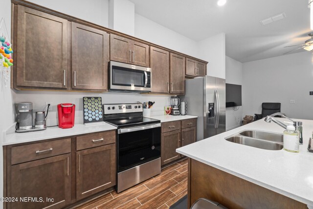 kitchen with stainless steel appliances, wood tiled floor, light countertops, and a sink