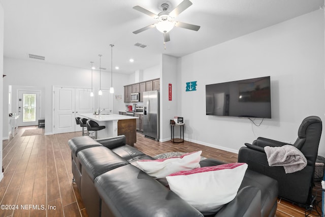 living room featuring wood finished floors, visible vents, and baseboards