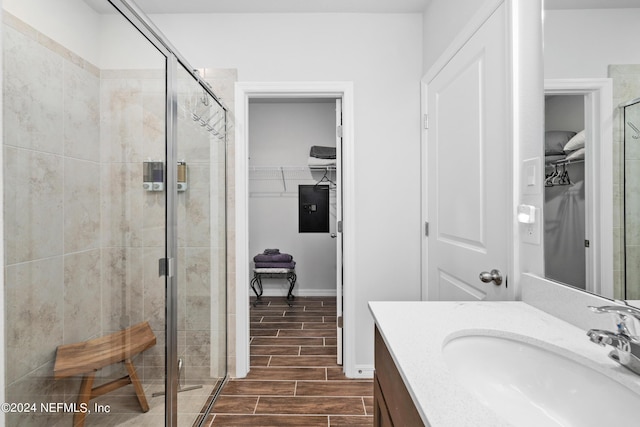 bathroom featuring a shower stall, vanity, a spacious closet, and wood finish floors