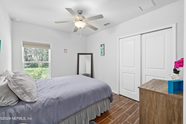 bedroom featuring a ceiling fan, wood tiled floor, visible vents, and a closet